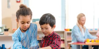 kids folding educational game with teacher at background in montessori class