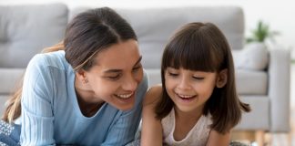 Mother and daughter lying on warm floor reading book