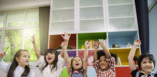 Group of multi-ethnic five little kids children African American, asian and Caucasian happiness together with friend to draw colour pencil to full colour of picture in living room or class room