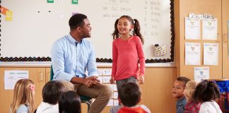 Schoolgirl at the front of elementary class with teacher